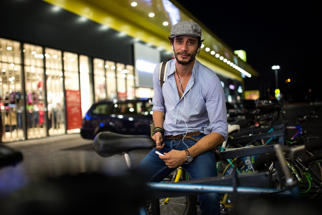 En man lutar sig mot parkerade cyklar, har hörlurar i öronen